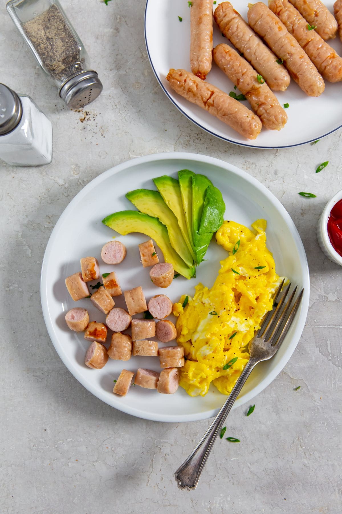 plate with sausage, eggs, and avocado slices.