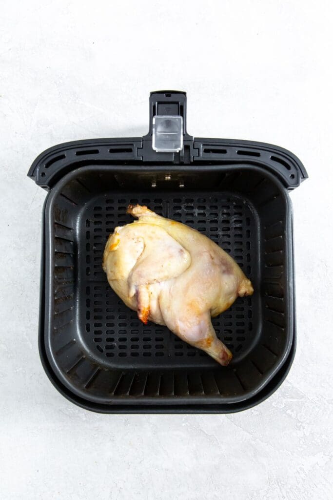 black air fryer basket with almost cooked chicken inside