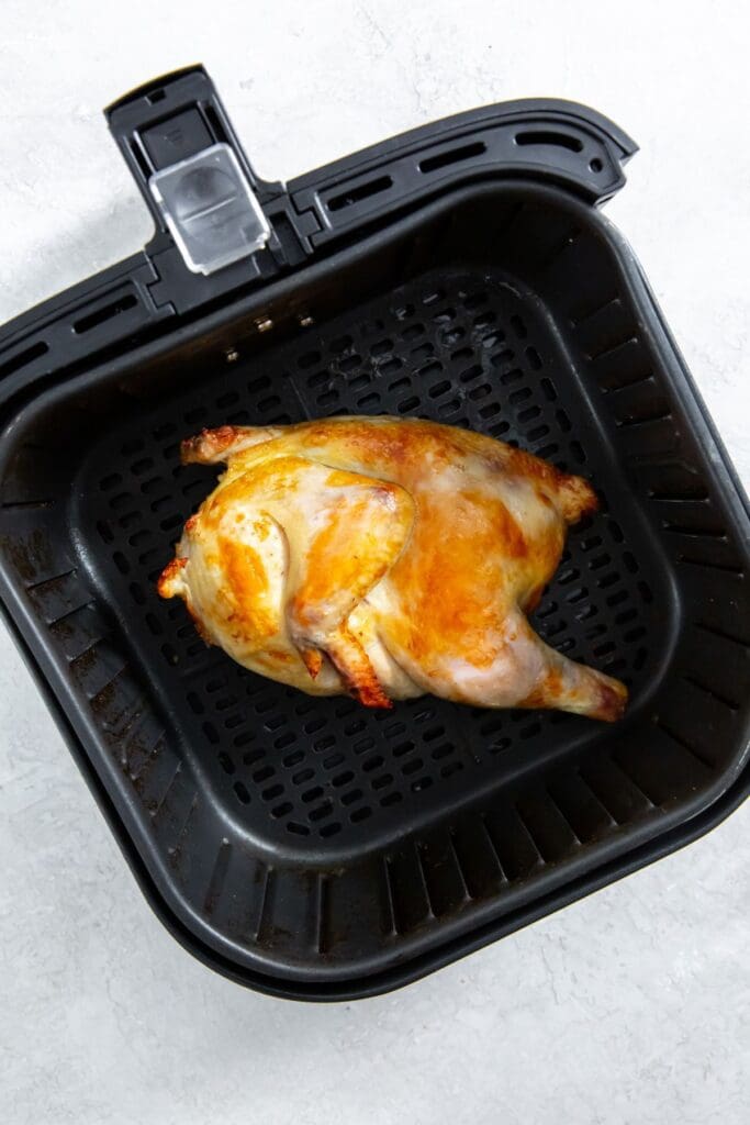 black air fryer basket with cooked chicken inside