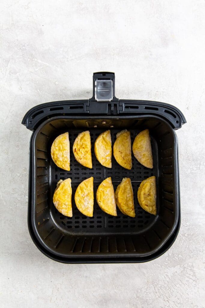 black air fryer basket with uncooked mini tacos inside