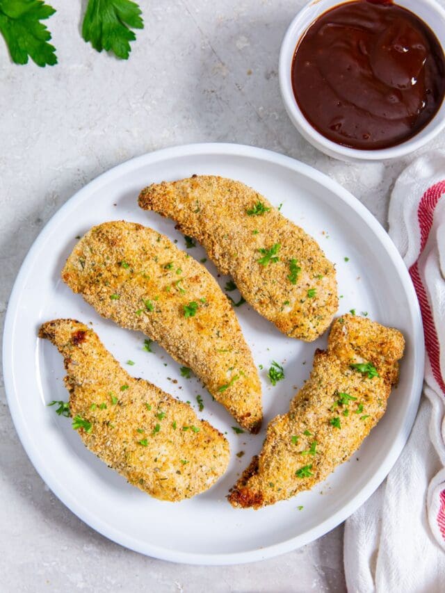 white plate with chicken on it. parsley and white a, pink towel in the back bbq sauce next to it