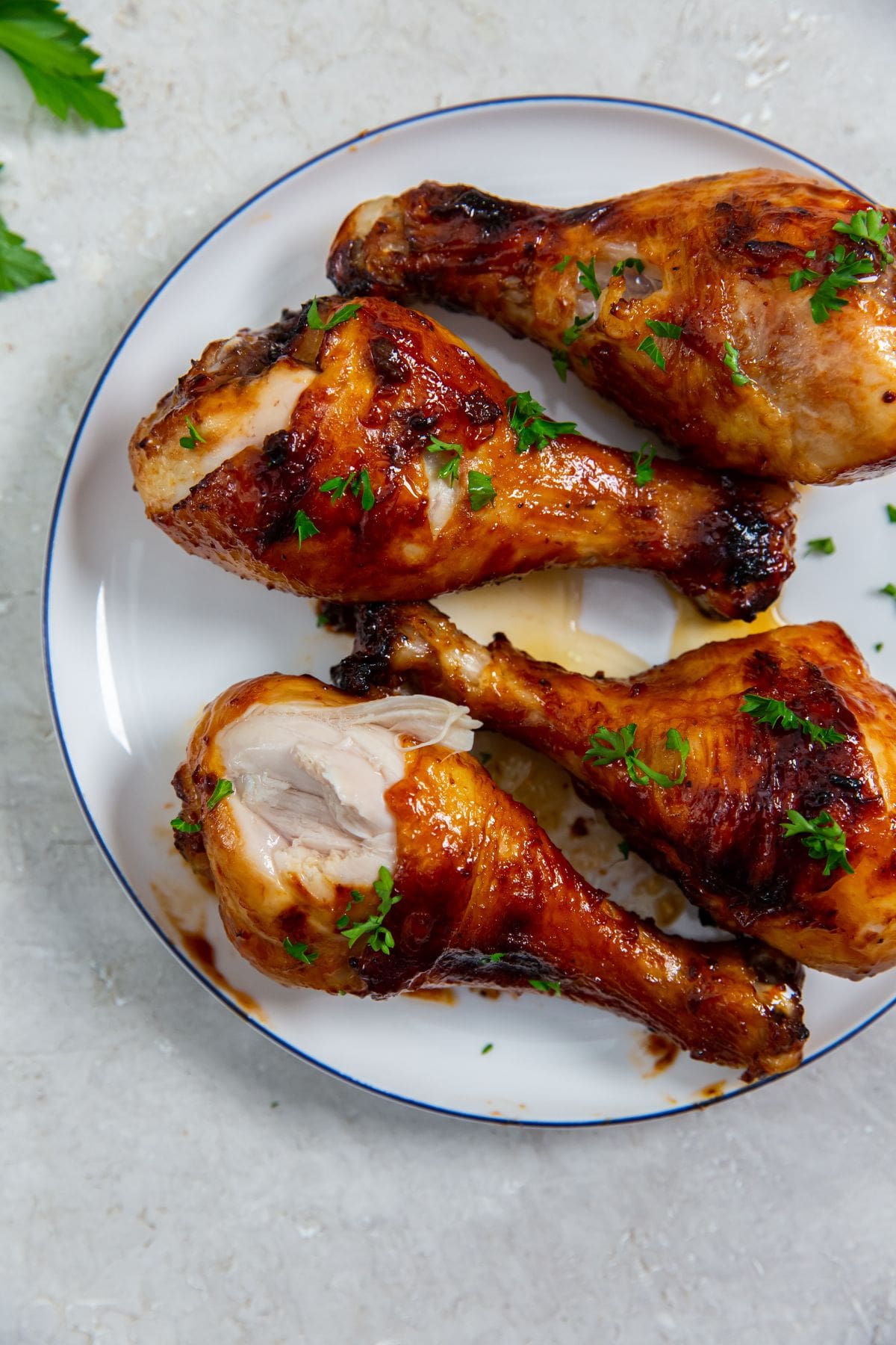 white plate with chicken on it. parsley sprinkled on top and parsley in the back