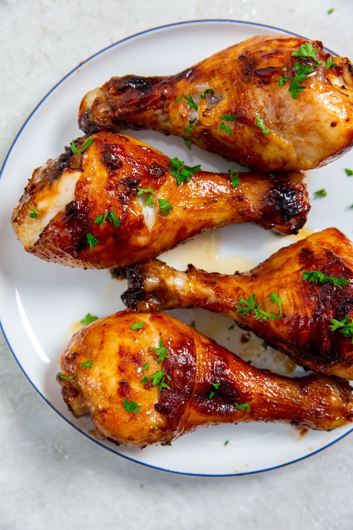 white plate with chicken on it. parsley sprinkled on top and parsley in the back