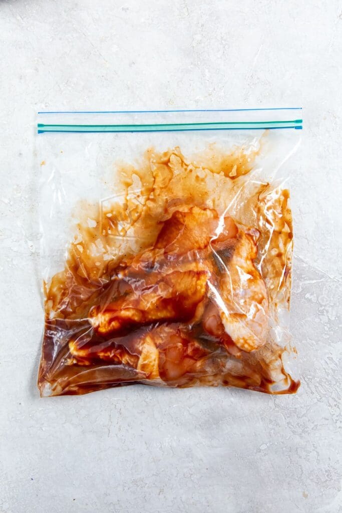 chicken tossed around in sauce inside a ziplock bag