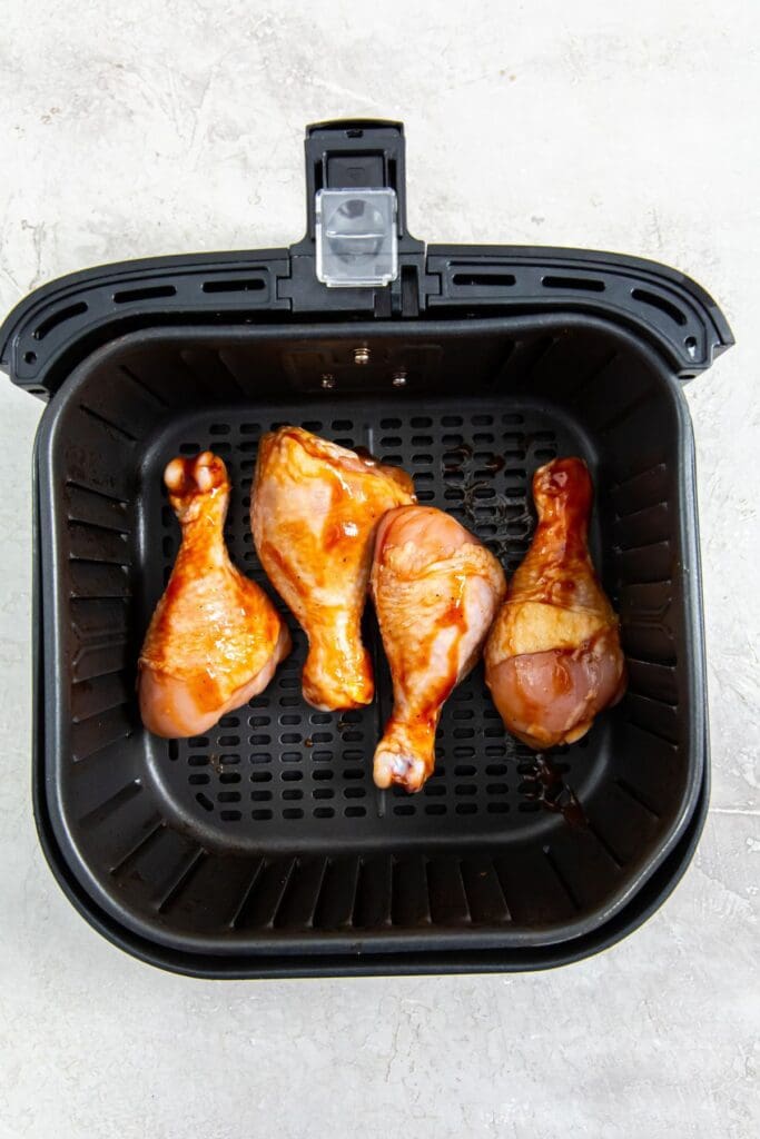 black air fryer basket with raw chicken inside