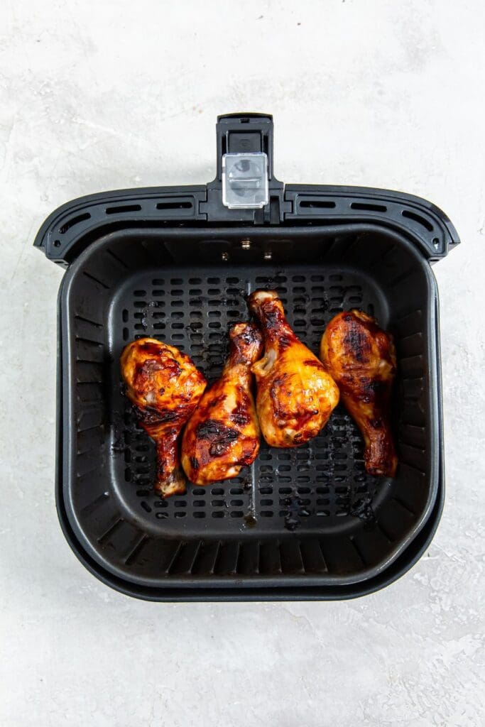 black air fryer basket with cooked chicken inside