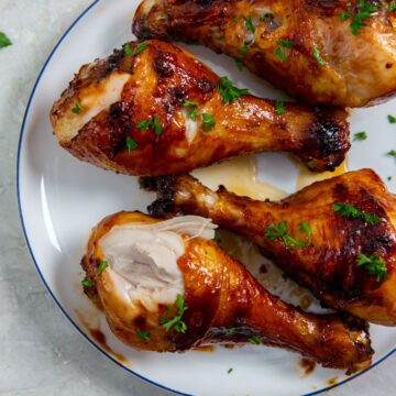 white plate with chicken on it. parsley sprinkled on top and parsley in the back