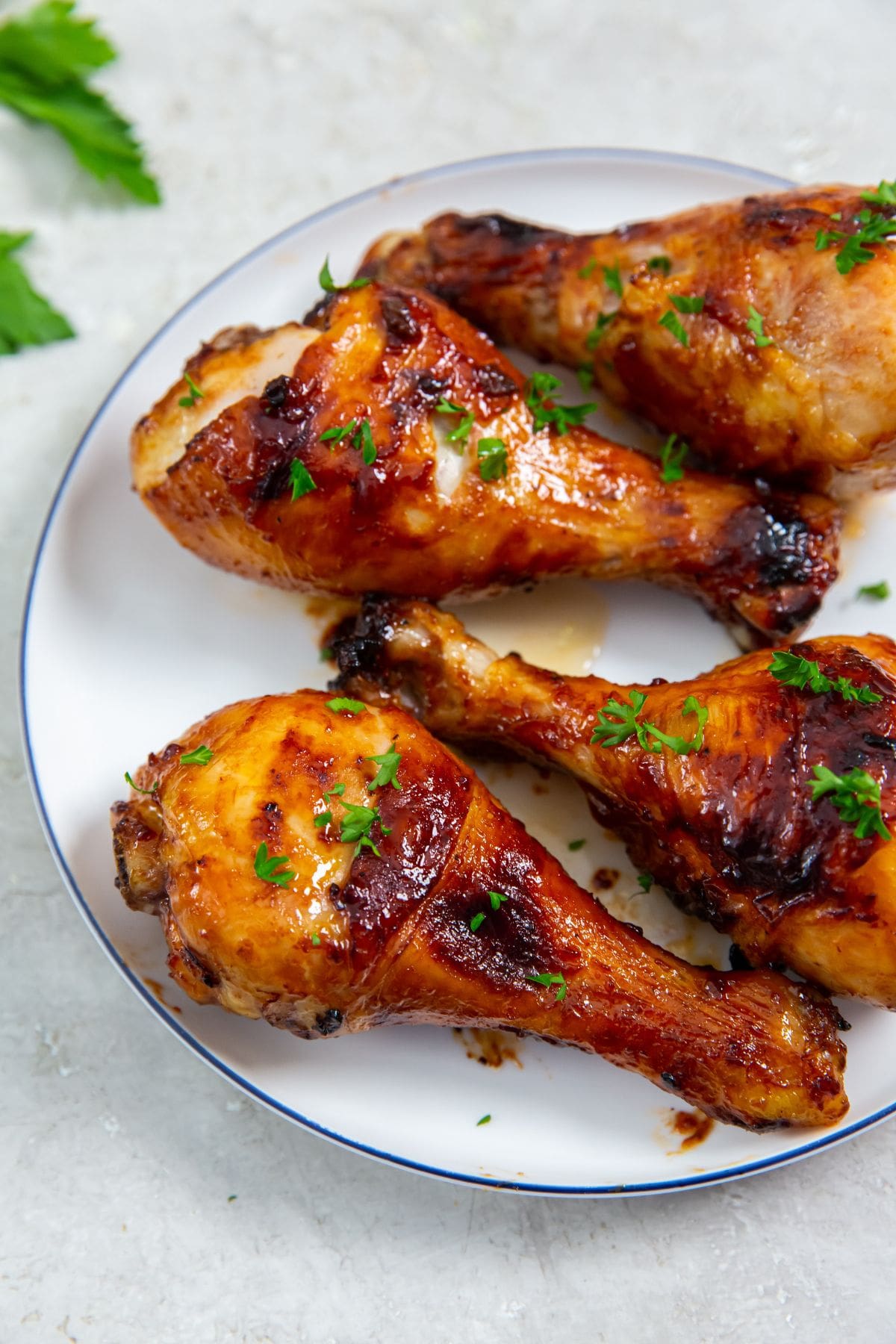 white plate with chicken on it. parsley sprinkled on top and parsley in the back