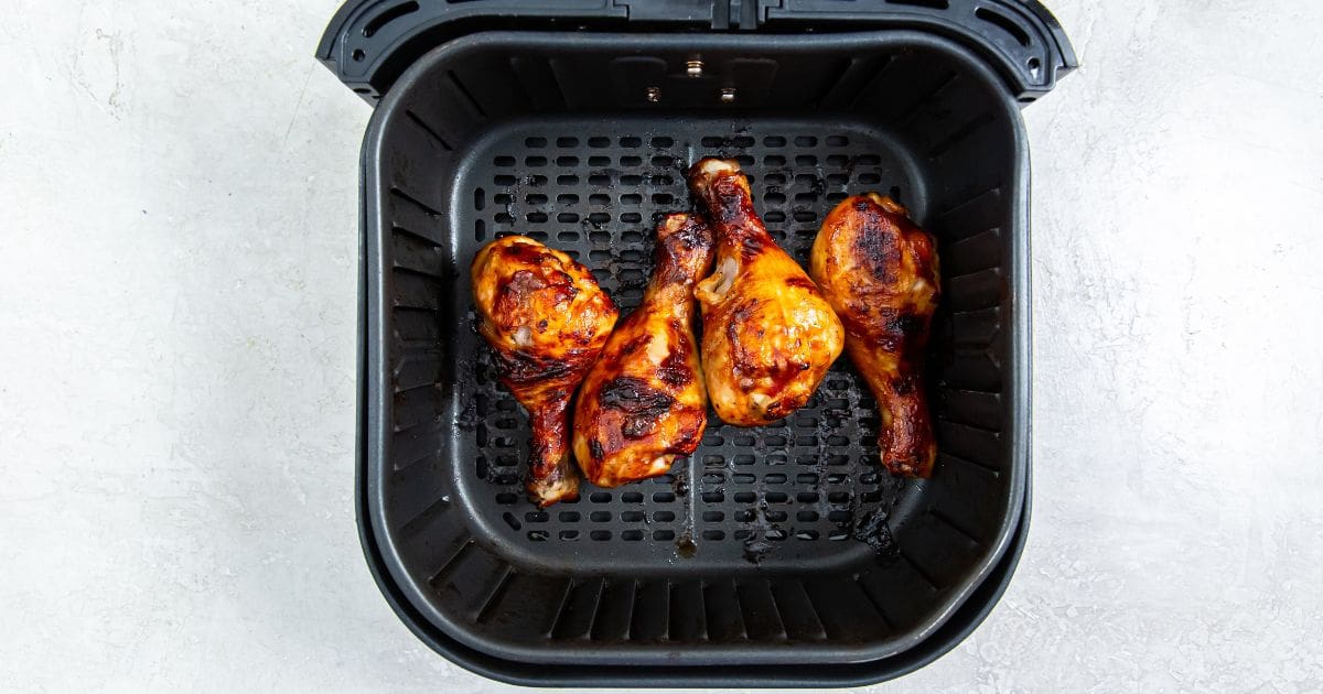 black air fryer with cooked chicken inside