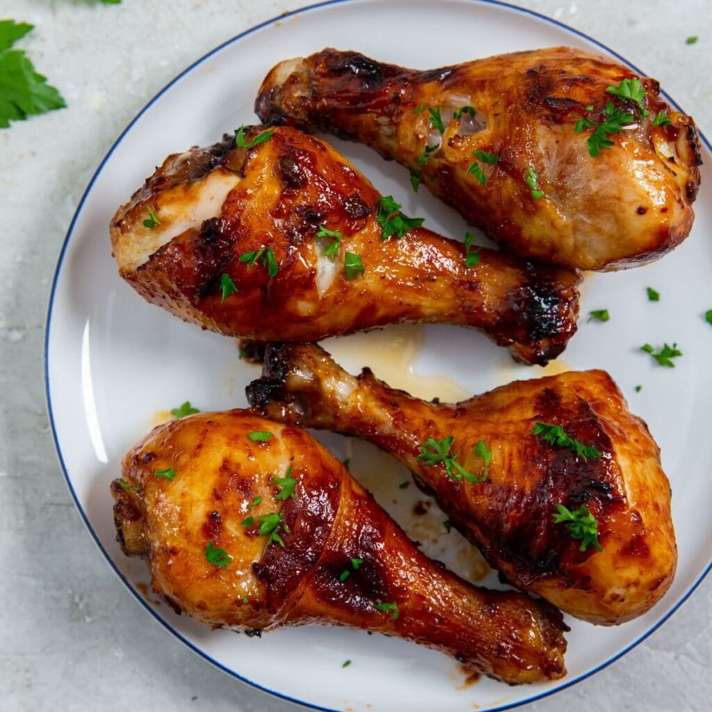 white plate with chicken on it. parsley sprinkled on top and parsley in the back