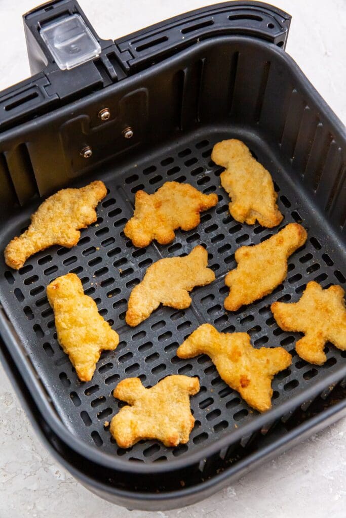 black air fryer basket with cooked chicken inside