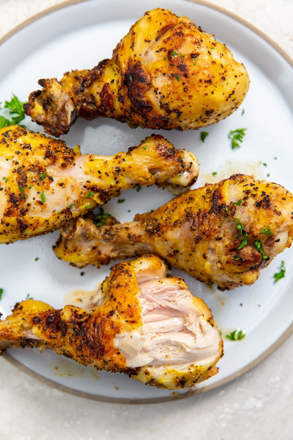 white plate with chicken legs on them. parsley sprinkled on top.