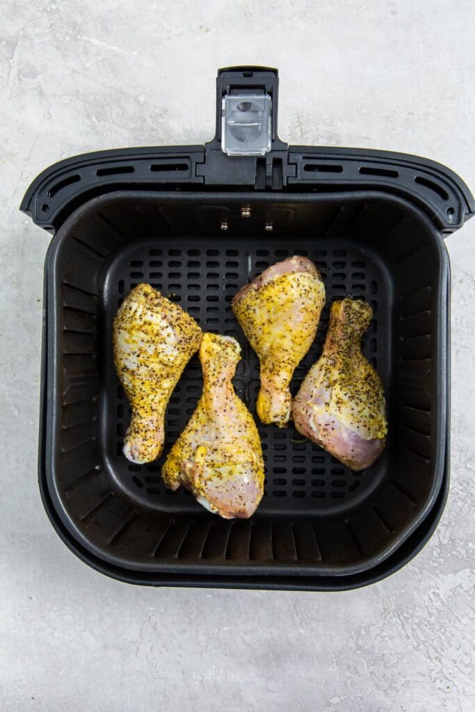 black air fryer basket with raw chicken inside