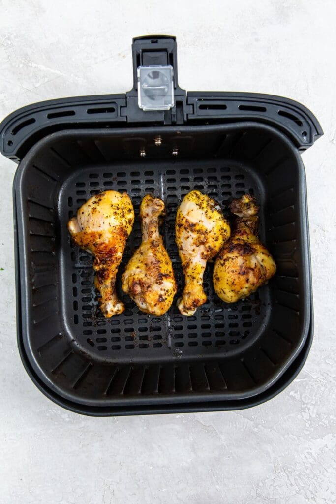 black air fryer basket with cooked chicken inside