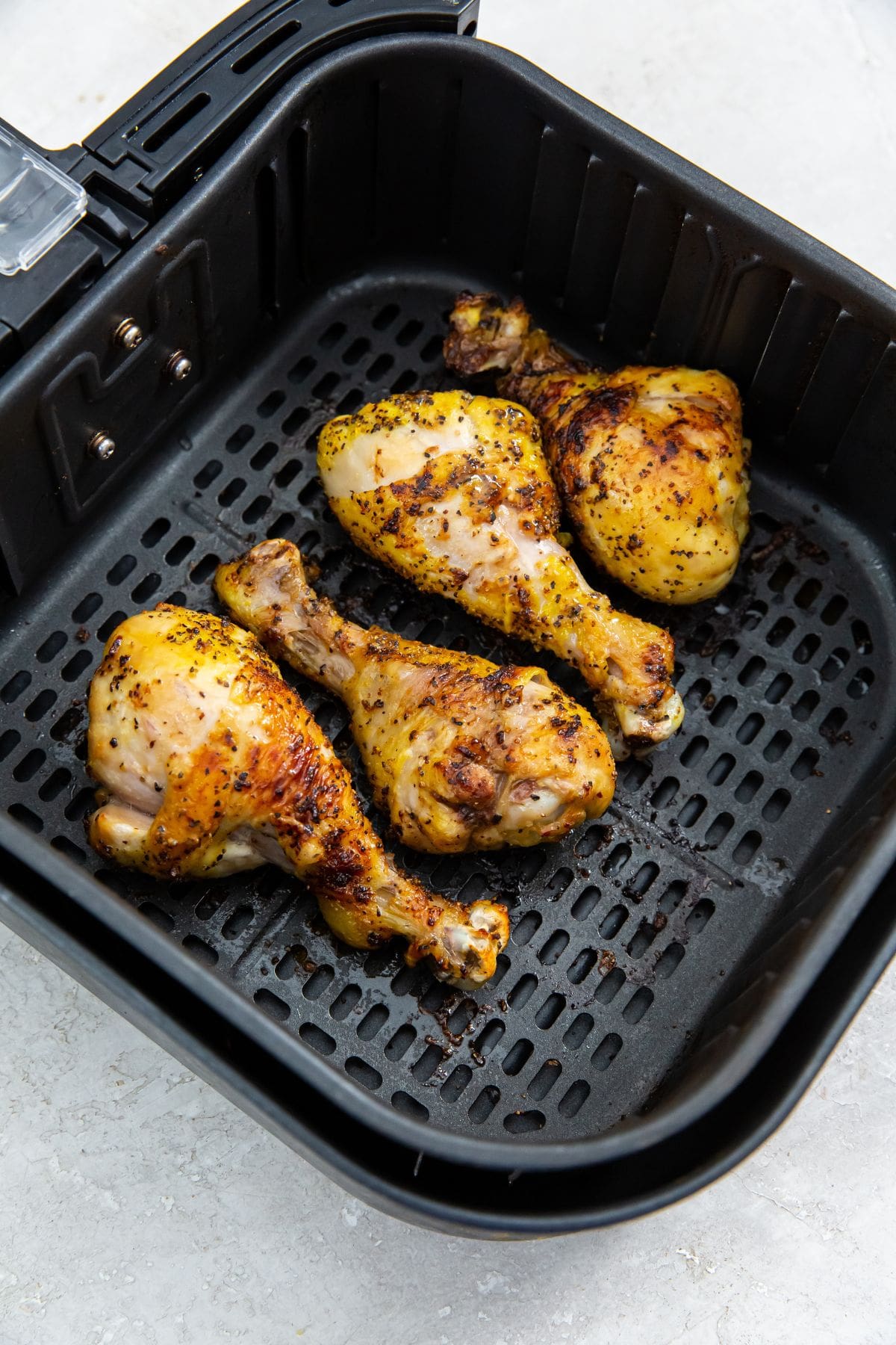 black air fryer basket with cooked chicken inside