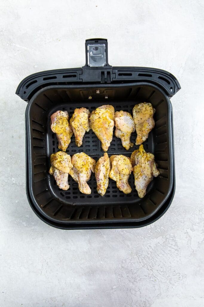 black air fryer basket with raw chicken inside