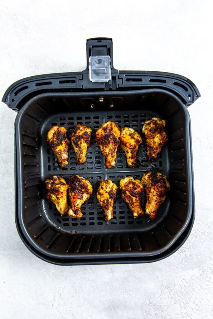 black air fryer basket with cooked chicken inside