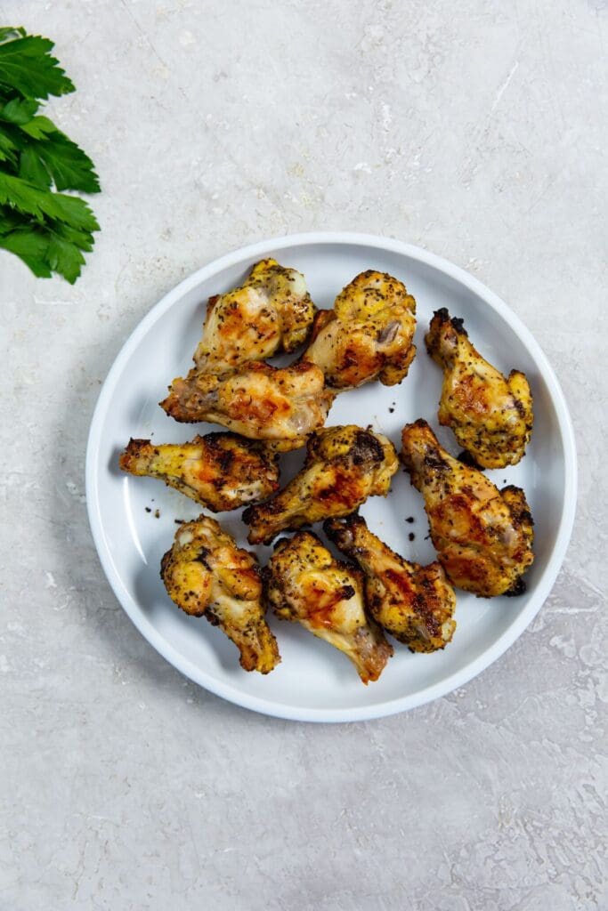 white plate with chicken and parsley in the back.