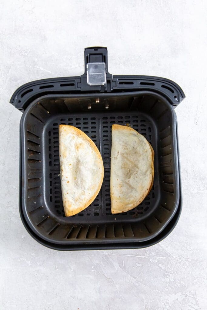 black air fryer basket with cooked quesadillas inside