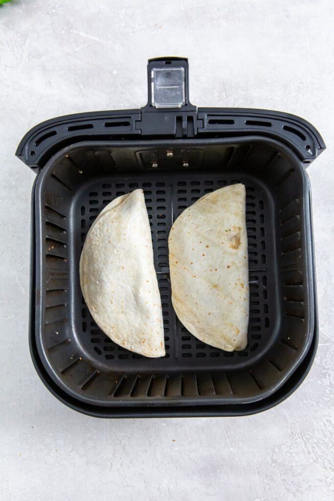 black air fryer basket with frozen quesadilla inside