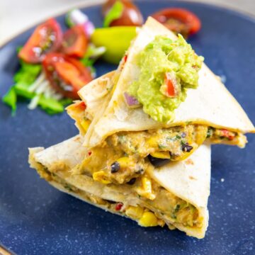 blue plate with a quesadilla on it. guacamole on top.