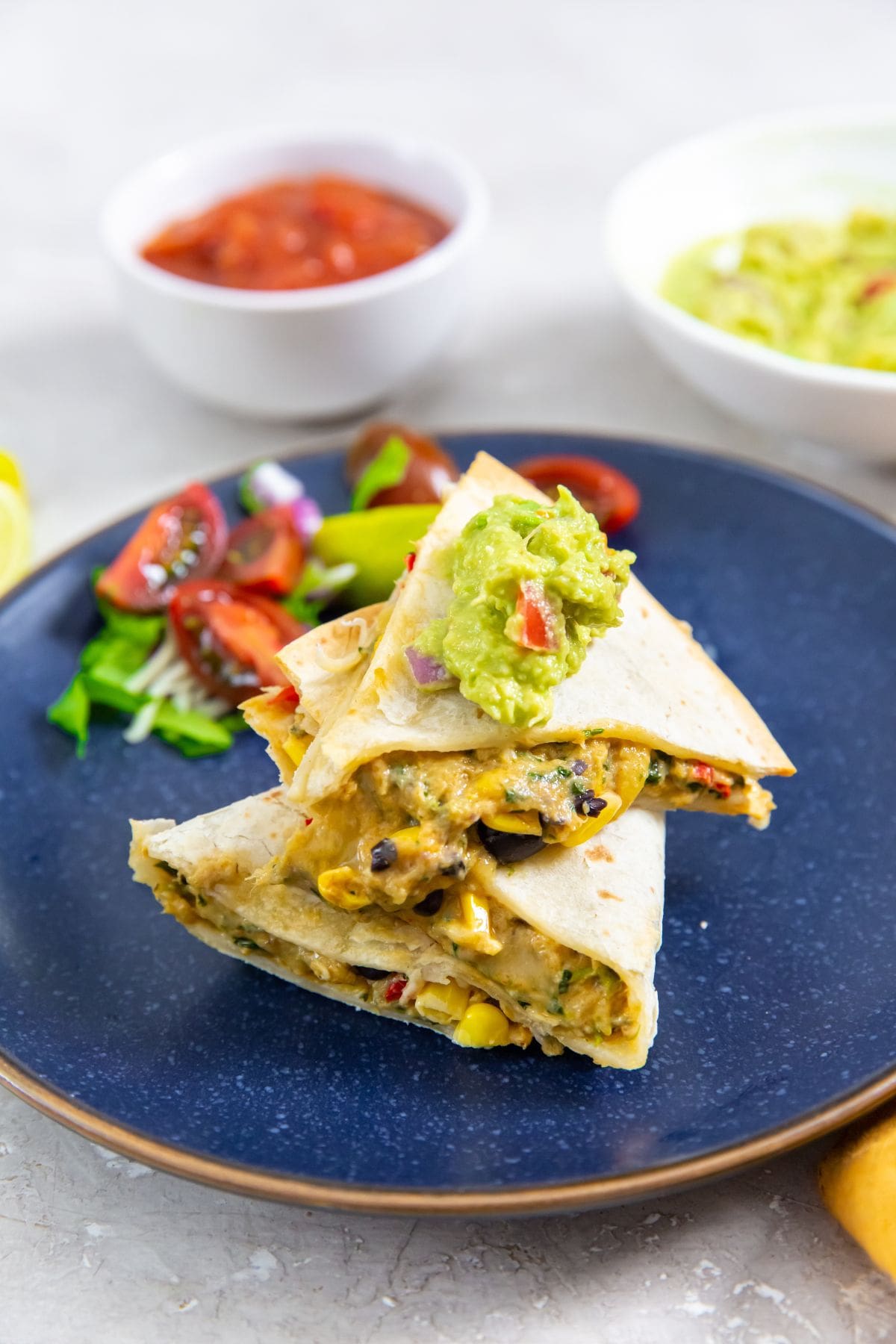 blue plate with a quesadilla on it. guacamole on top.