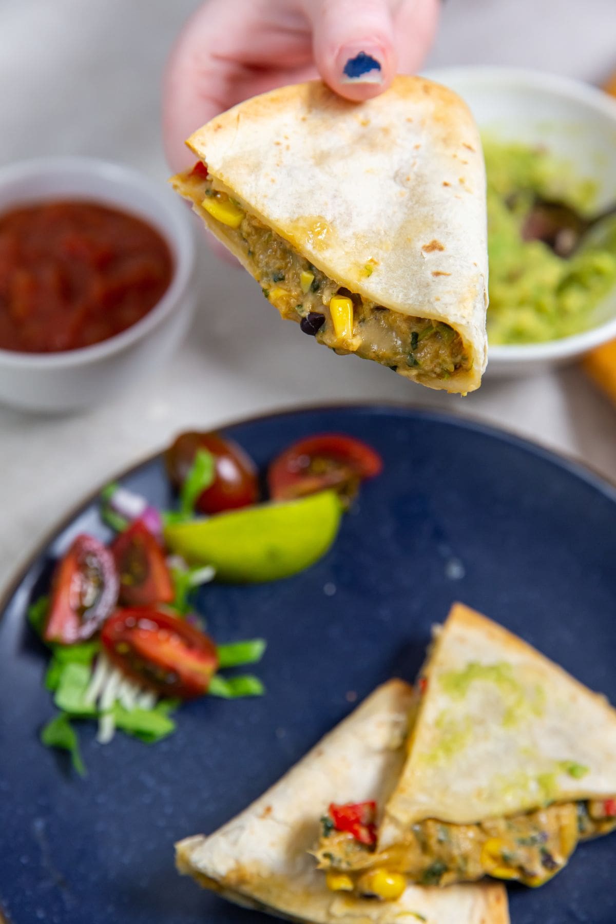 blue plate with a quesadilla on it. guacamole on top.