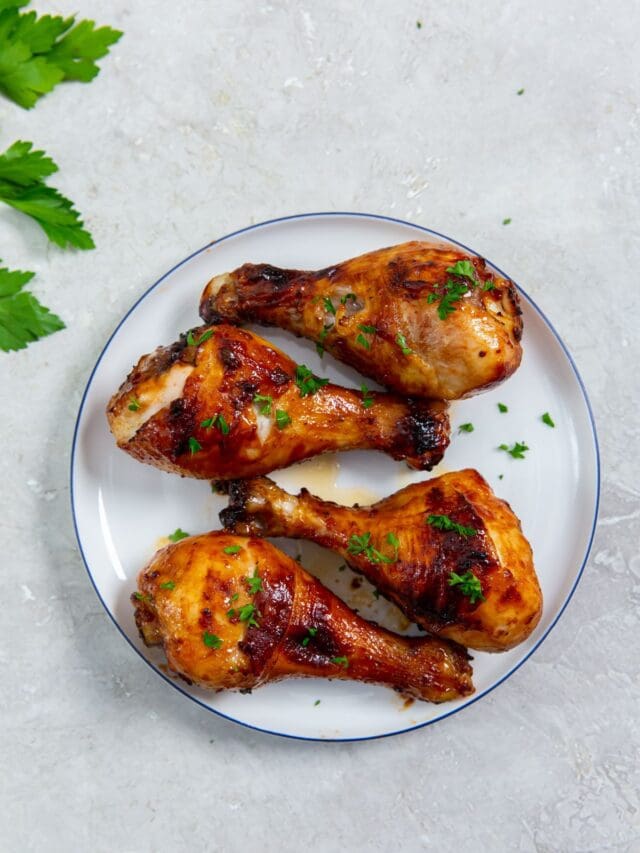 white plate with chicken on it. parsley sprinkled on top and parsley in the back