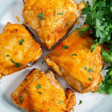 white plate with chicken and parsley on it.