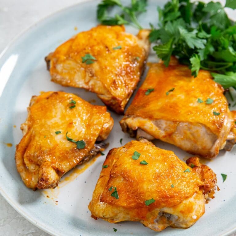 white plate with chicken and parsley on it.