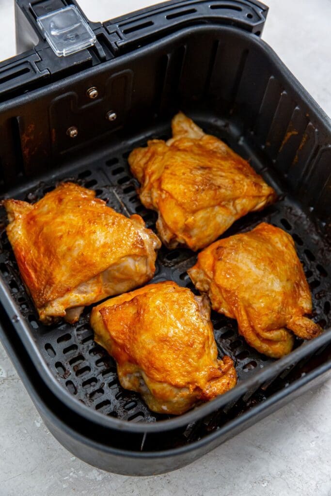 black air fryer basket with cooked chicken inside