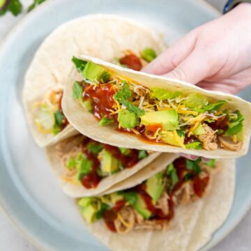 tacos on a plate and person holding one