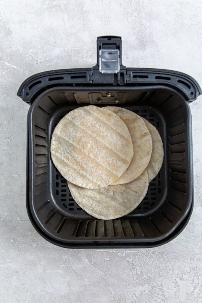 black air fryer basket with tortillas inside