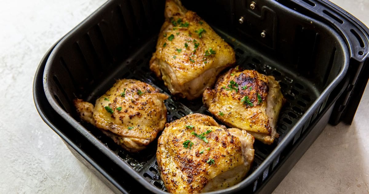 black air fryer basket with cooked chicken inside 