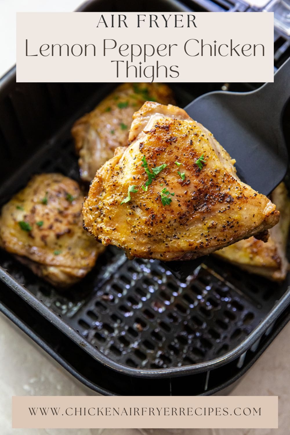 black air fryer basket with cooked chicken inside. spatula holding chicken