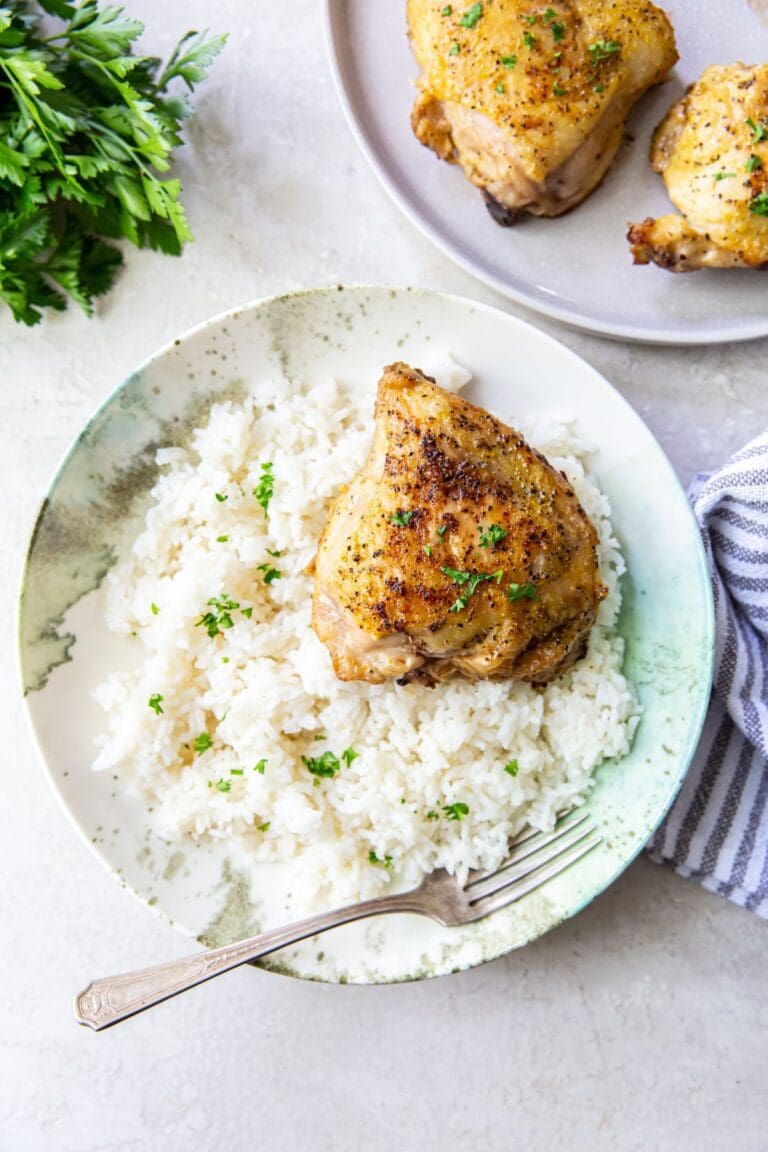 white bowl with rice and chicken inside. chicken in the background