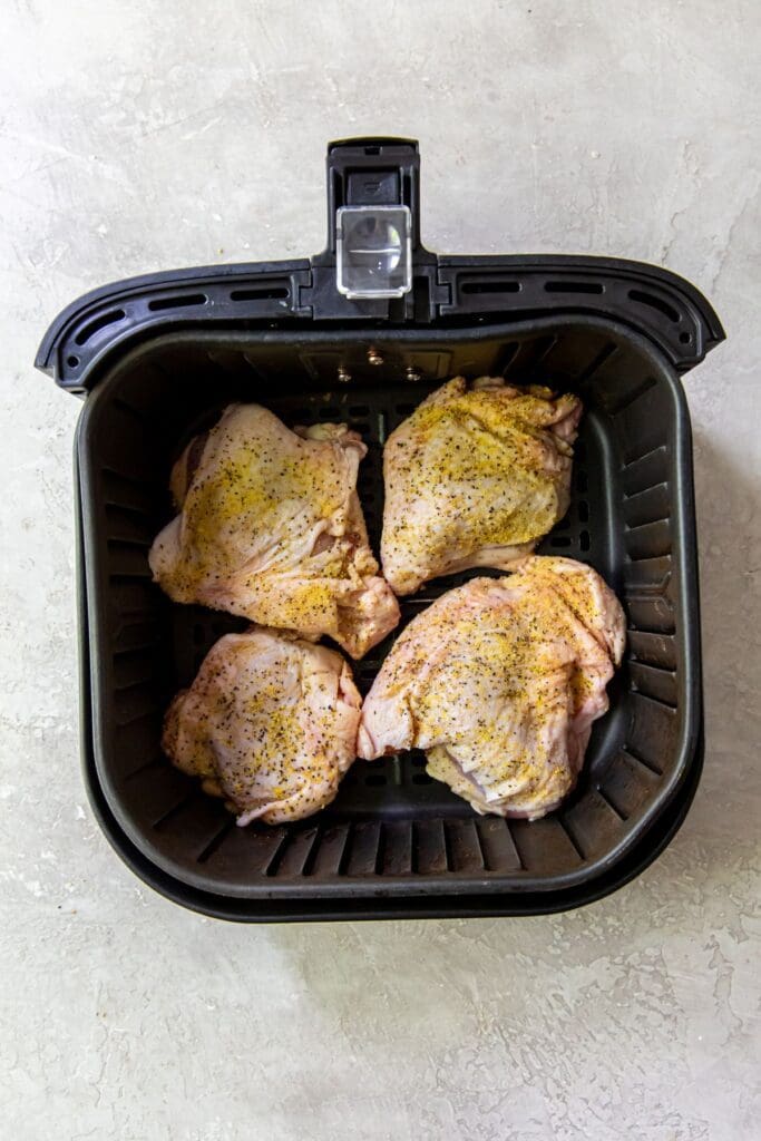 black air fryer basket with raw chicken inside