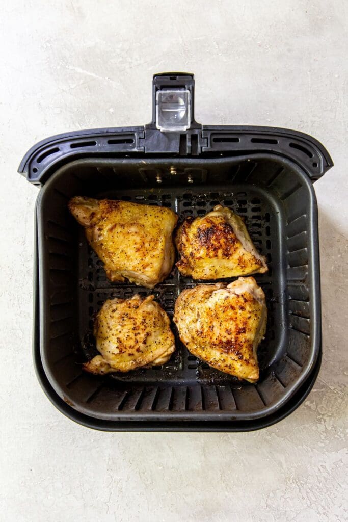 black air fryer basket with cooked chicken inside