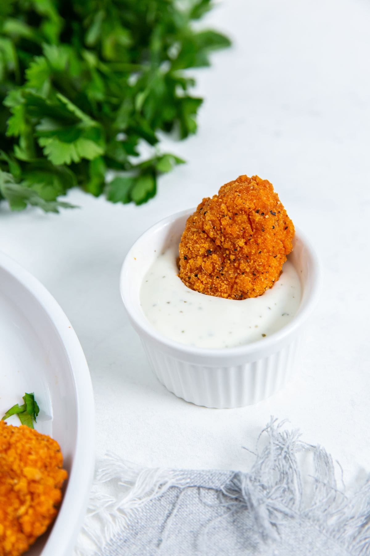 chicken nugget dunked in ranch. Parsley in the background.