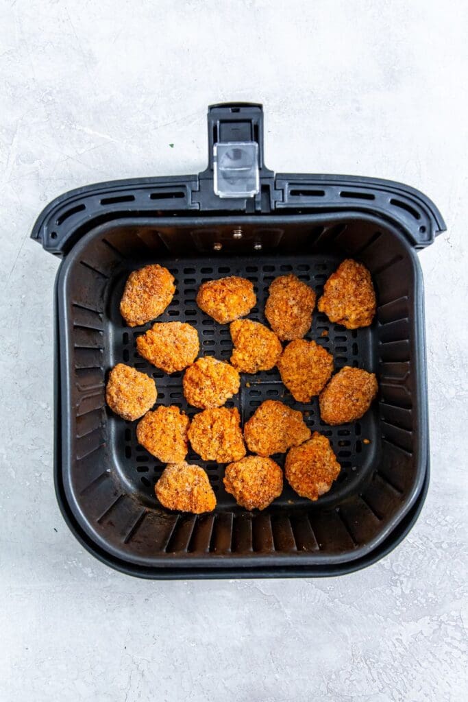 black air fryer basket with raw chicken inside