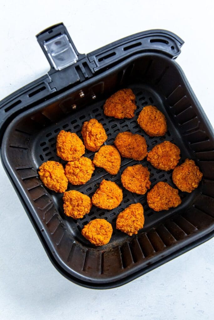 black air fryer basket with cooked chicken inside