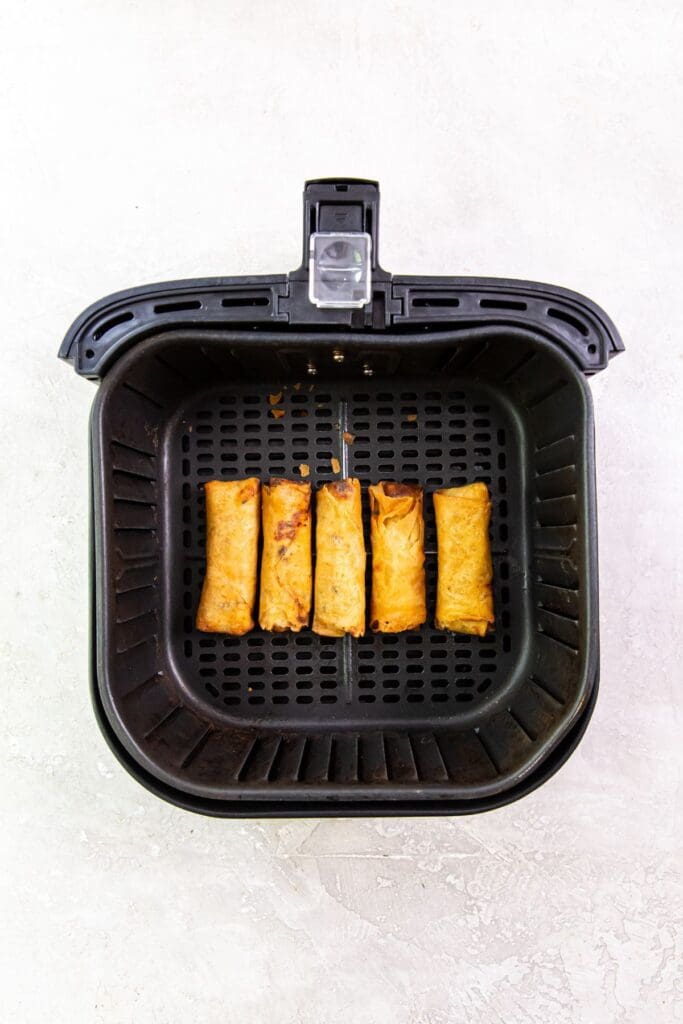 black air fryer basket with cooked chicken inside