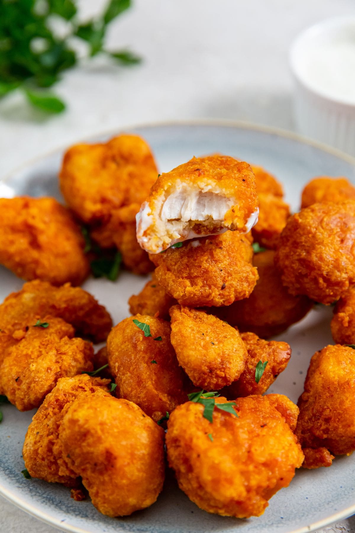 white plate with Tyson Boneless Chicken Bites in the Air Fryer with parsley and ranch in the back.