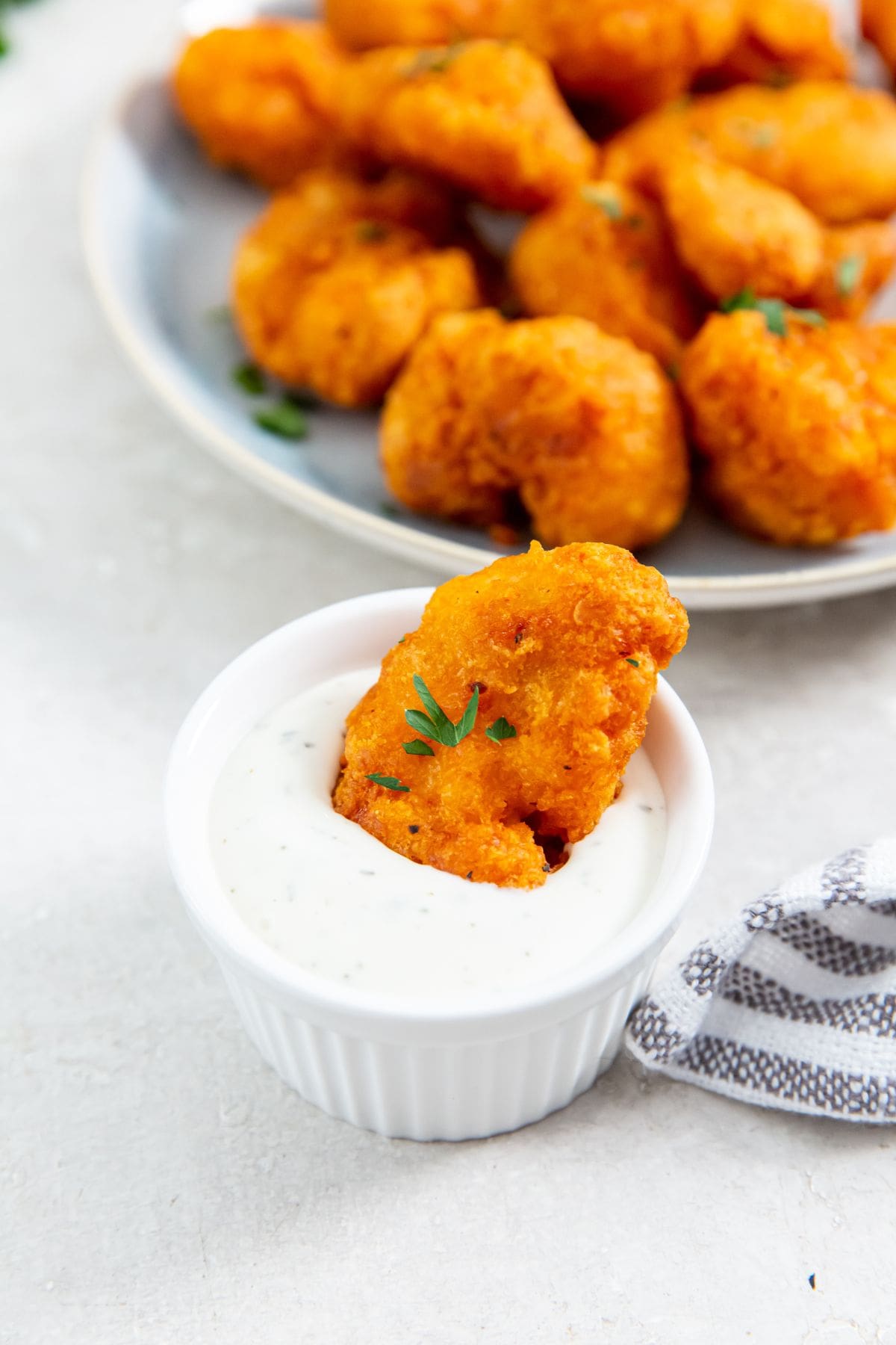 chicken dipped in ranch. plate full of chicken in the background.