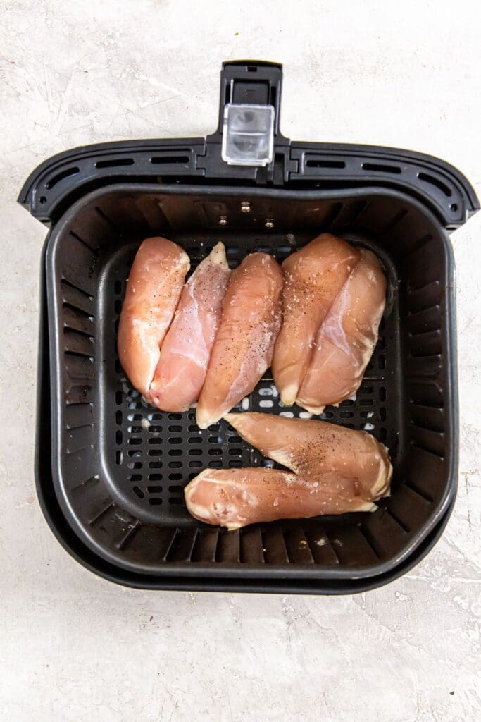 black air fryer basket with chicken inside