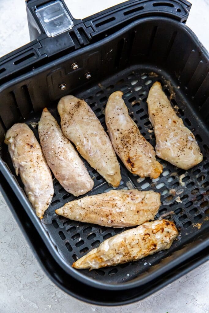 black air fryer basket with cooked chicken inside