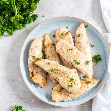 blue plate with chicken on it. parsley and towel in the back.