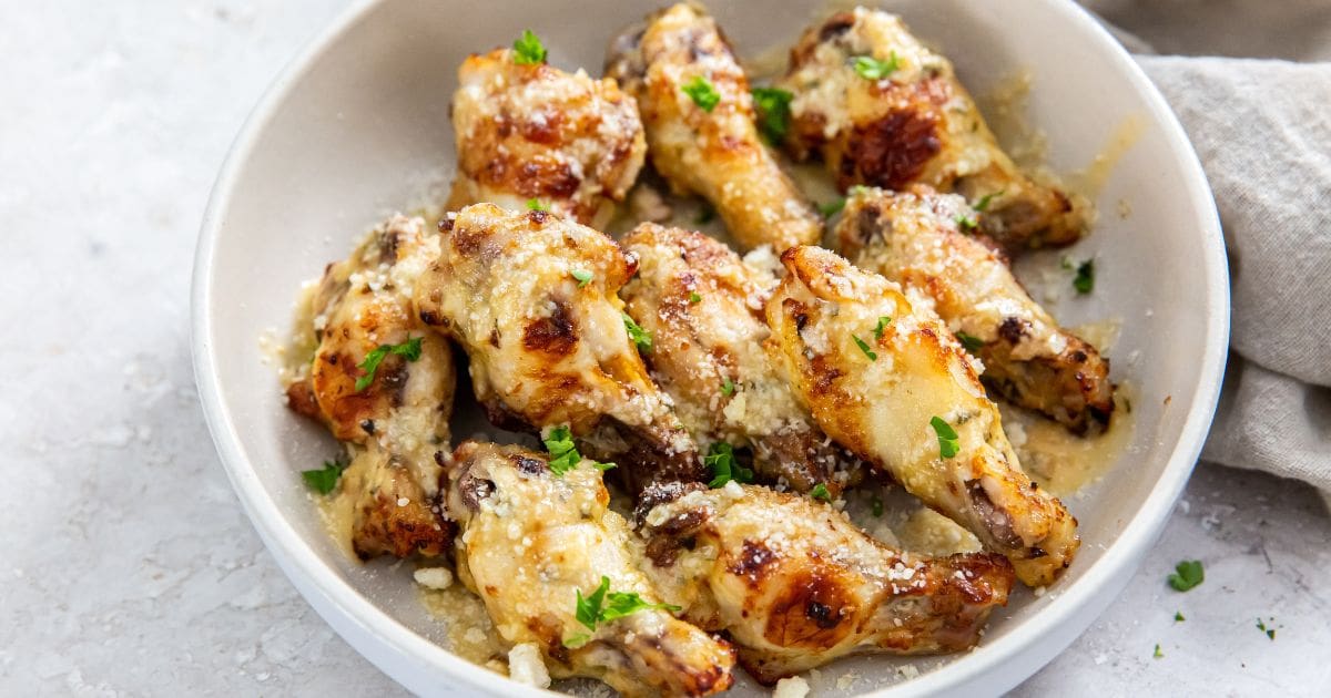 garlic Parmesan wings in white bowl. gray towel next to it.