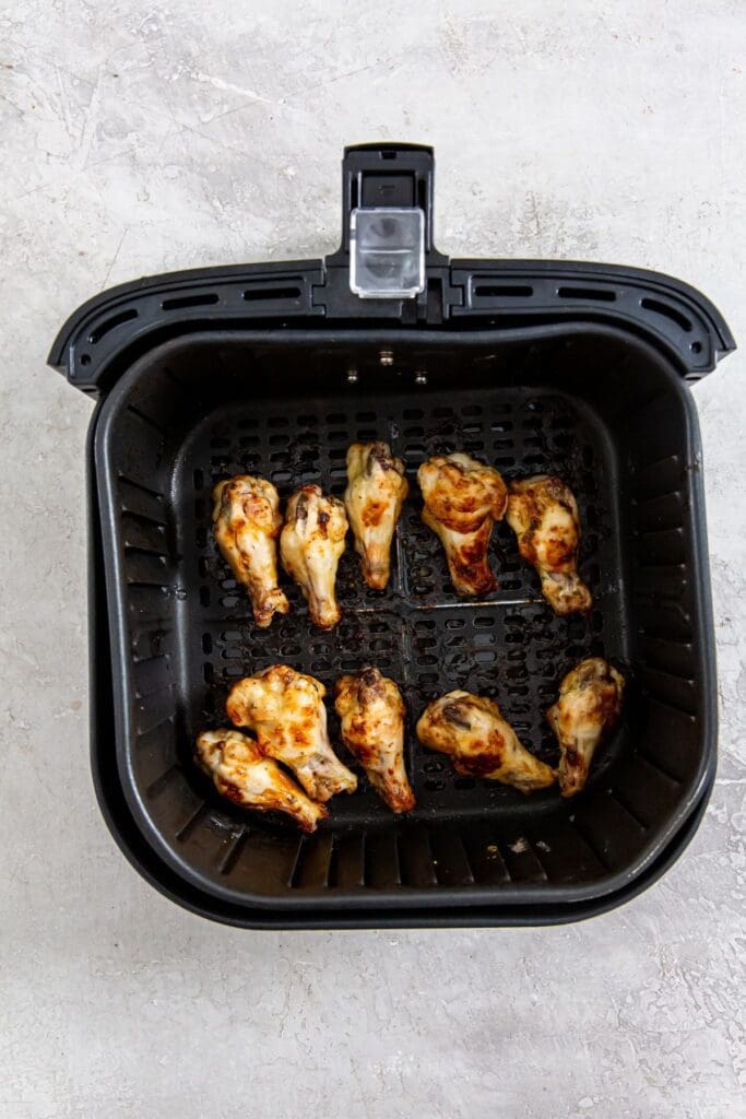 black air fryer basket with cooked wings inside