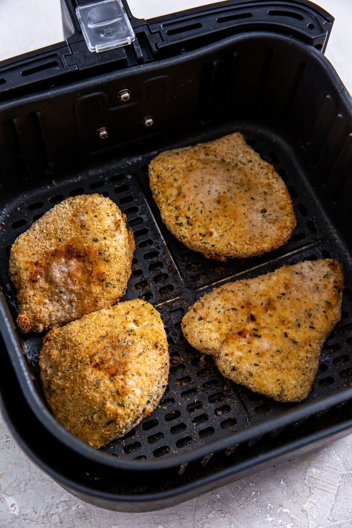 black air fryer basket with cooked chicken cutlets inside